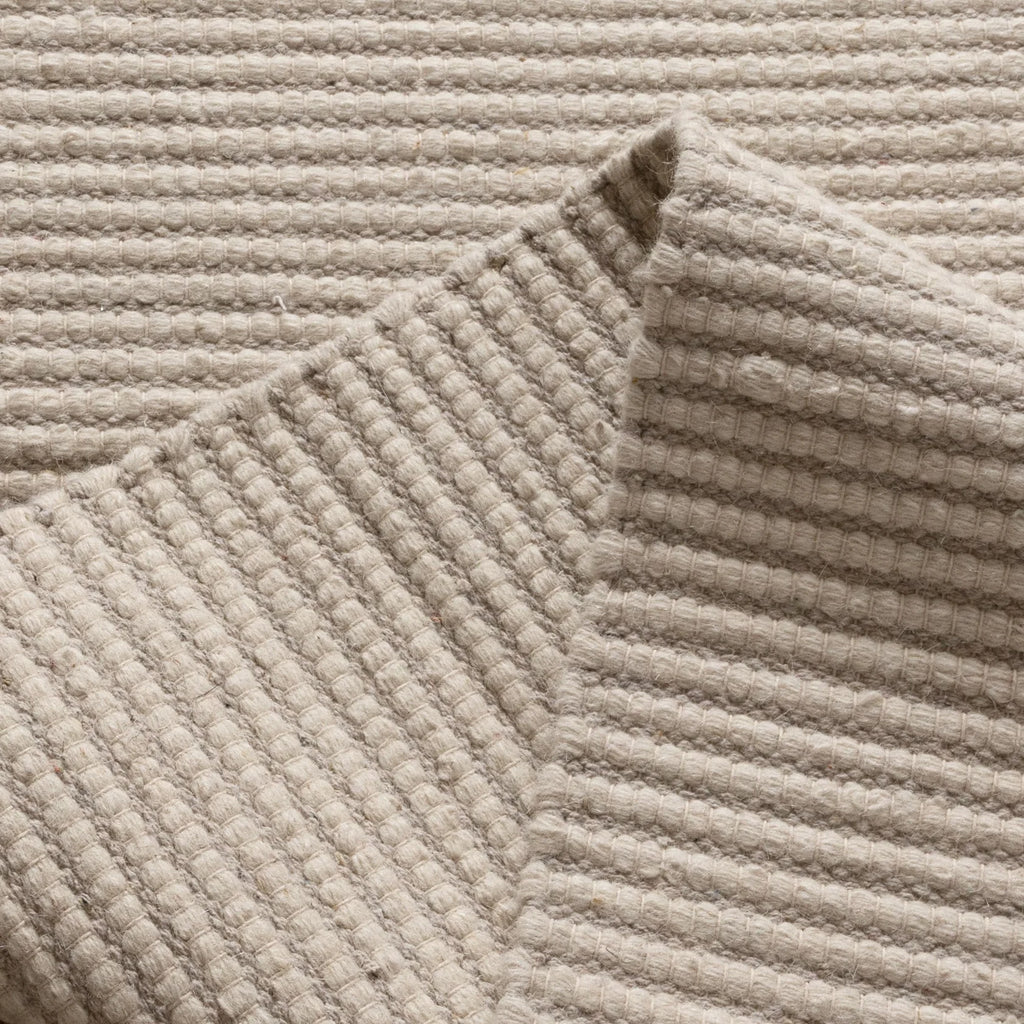 Close-up of a textured beige rug in a cream-ivory tone 
