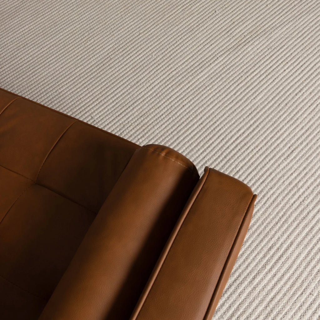 Brown leather sofa corner on a textured beige carpet