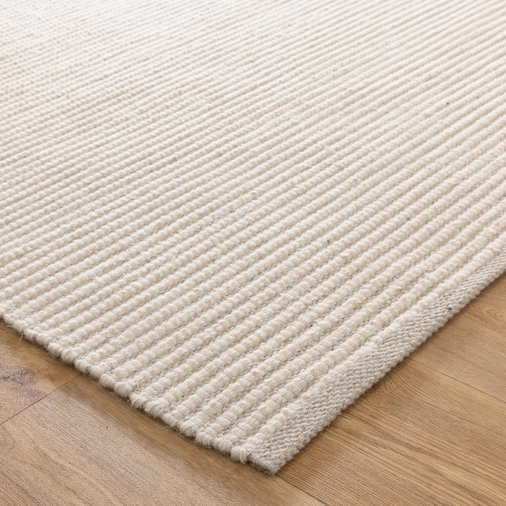 Beige handwovcen wool rug on a wooden floor