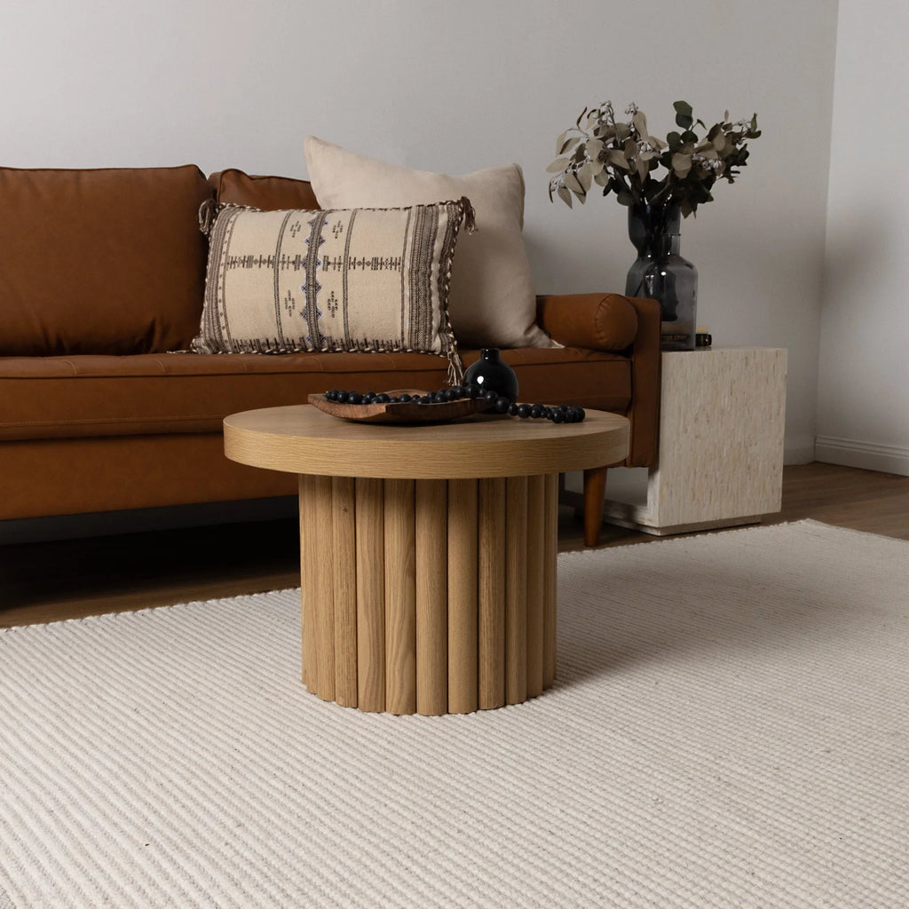 Living room with brown sofa, wooden coffee table, and decorative items placed on a cream-ivory wool rug